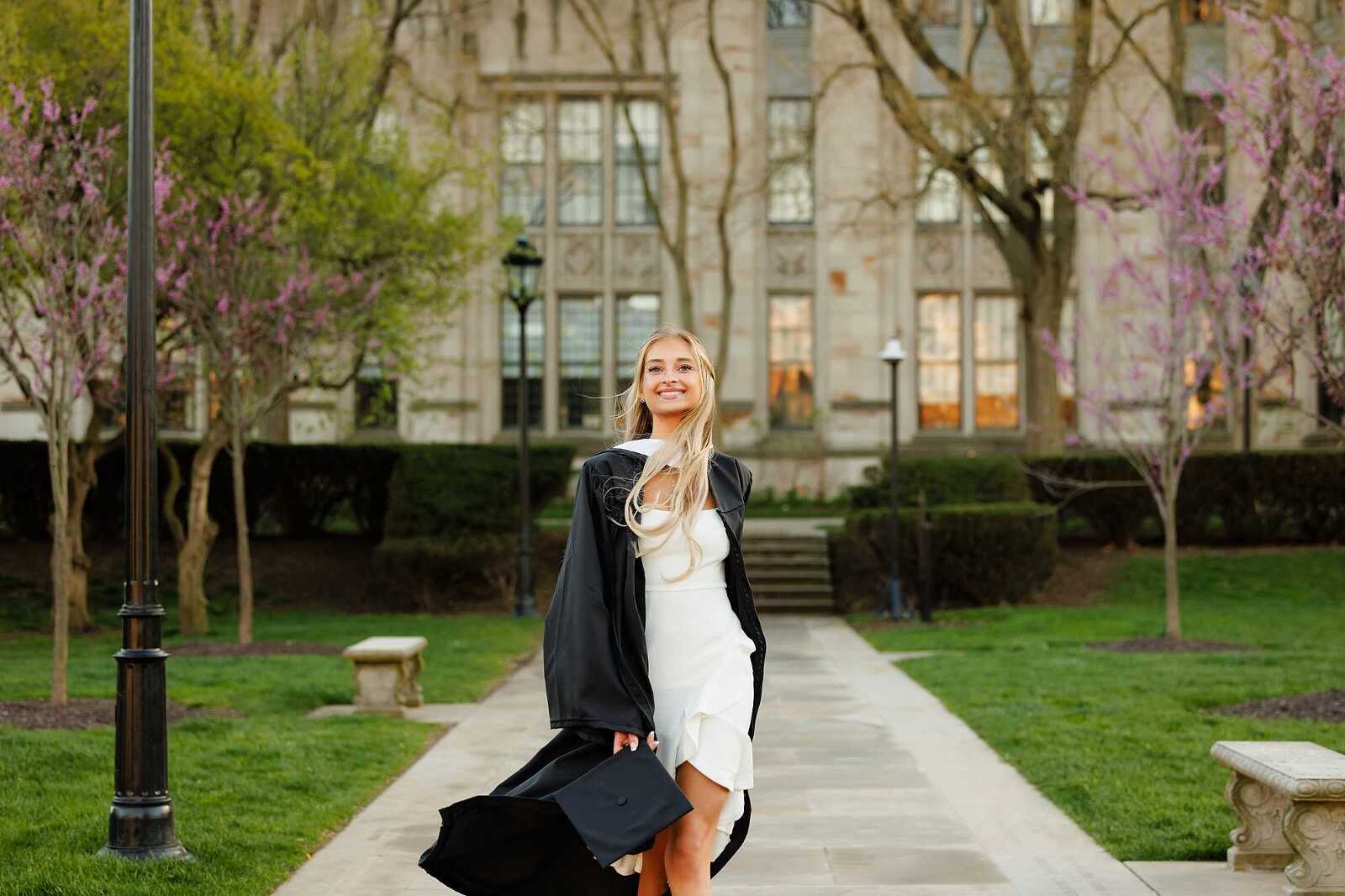 College Graduate standing on sidewalk in front of the Cathedral of Learning at the University of Pittsburgh