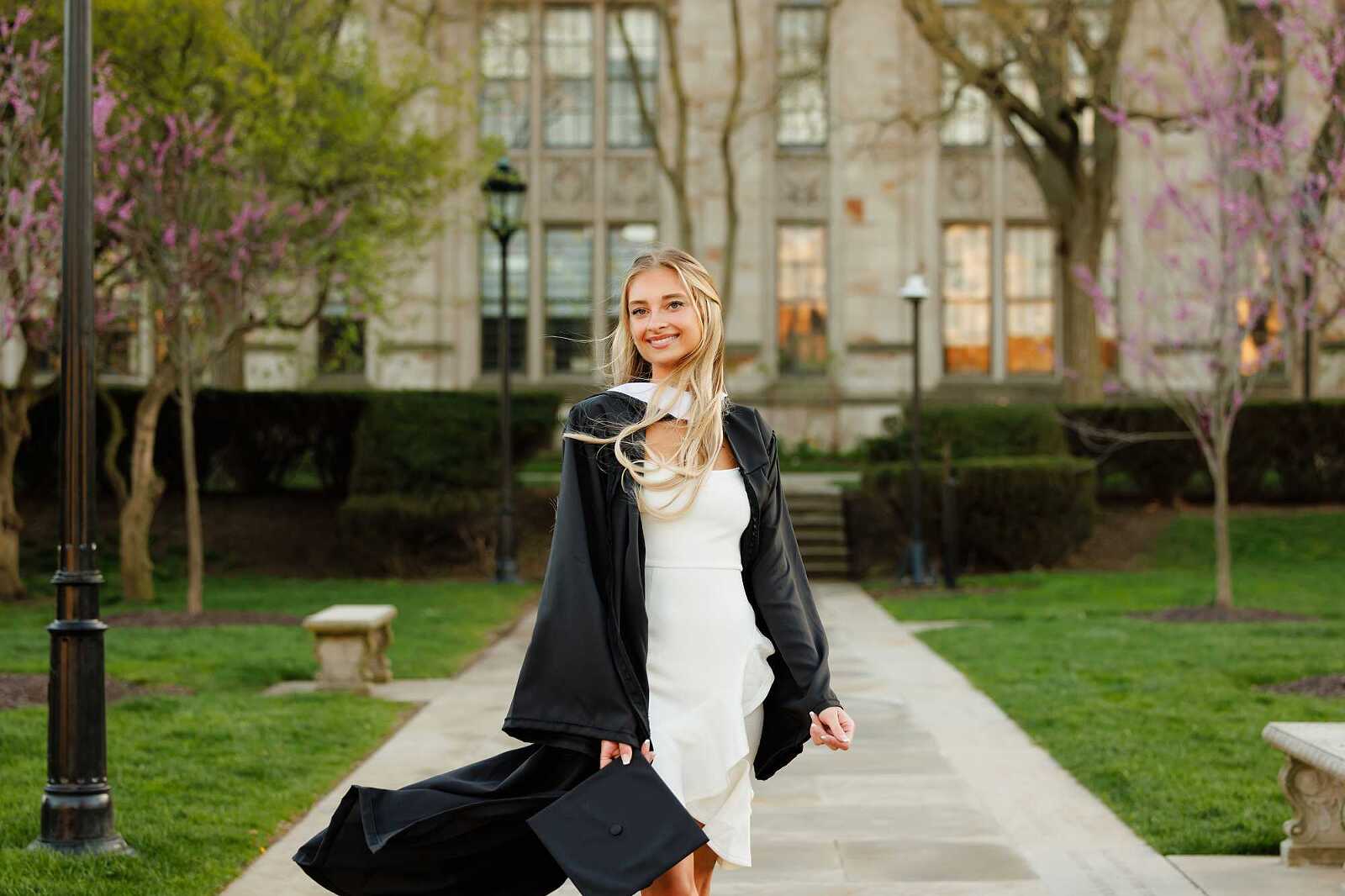 College Graduate standing on sidewalk in front of the Cathedral of Learning at the University of Pittsburgh