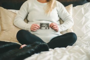 Pregnant woman sitting on bed in home in Sewickley near Pittsburgh