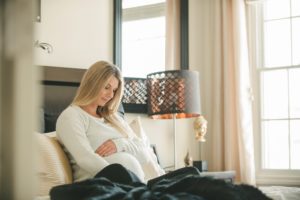 Pregnant woman sitting on bed in home in Sewickley near Pittsburgh