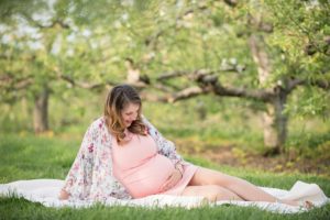 Pregnant woman sitting on the ground at Soergel Orchards near Pittsburgh