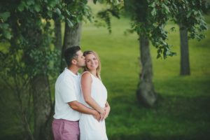 Husband kissing his pregnant wife on the cheek near Pittsburgh