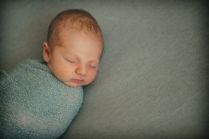 Newborn baby boy laying on gray blanket in photography studio in Moon Township near Pittsburgh