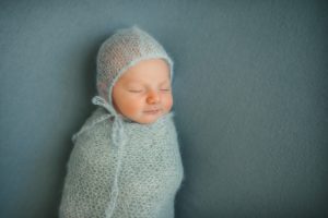 Newborn baby boy laying on blue blanket in photography studio in Moon Township near Pittsburgh