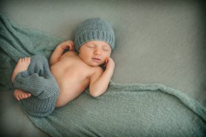 Newborn baby boy laying on blue blanket in photography studio in Moon Township near PIttsburgh