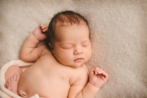 Newborn baby girl laying on cream blanket in photography studio in Moon Township near PIttsburgh