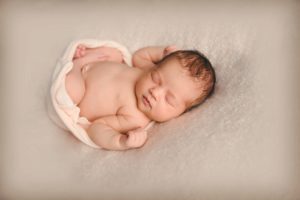 Newborn baby girl laying on cream blanket in photography studio in Moon Township near Pittsburgh