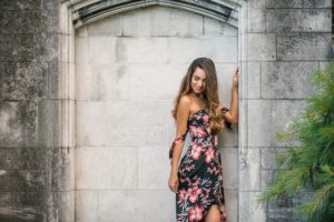 High School Senior girl standing next to stone wall in Mellon Park near PIttsburgh