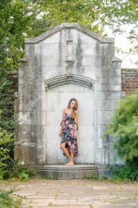 High school senior girl standing next to stone wall at Mellon Park near Pittsburgh