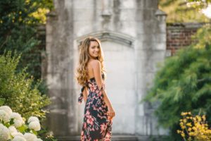 High school senior looking over shoulder in front of stone wall at Mellon Park near Pittsburgh