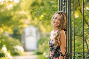 High school senior girl standing against wrought iron fence in Mellon Park near Pittsburgh