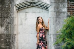 High school senior girl leaning up against stone wall in Mellon Park near Pittsburgh