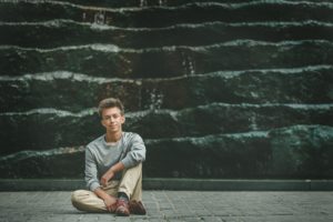 High school senior boy sitting in front of statue in downtown Pittsburgh