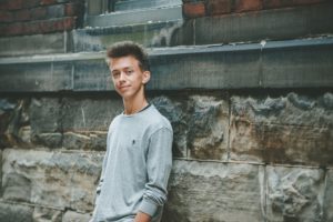 High school senior boy standing by stone wall in downtown Pittsburgh