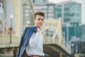 High school senior boy standing by bridge in downtown Pittsburgh