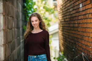 High school senior girl standing next to brick wall in Lawrenceville near Pittsburgh