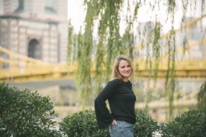 High school senior girl standing in front of bridge in downtown Pittsburgh