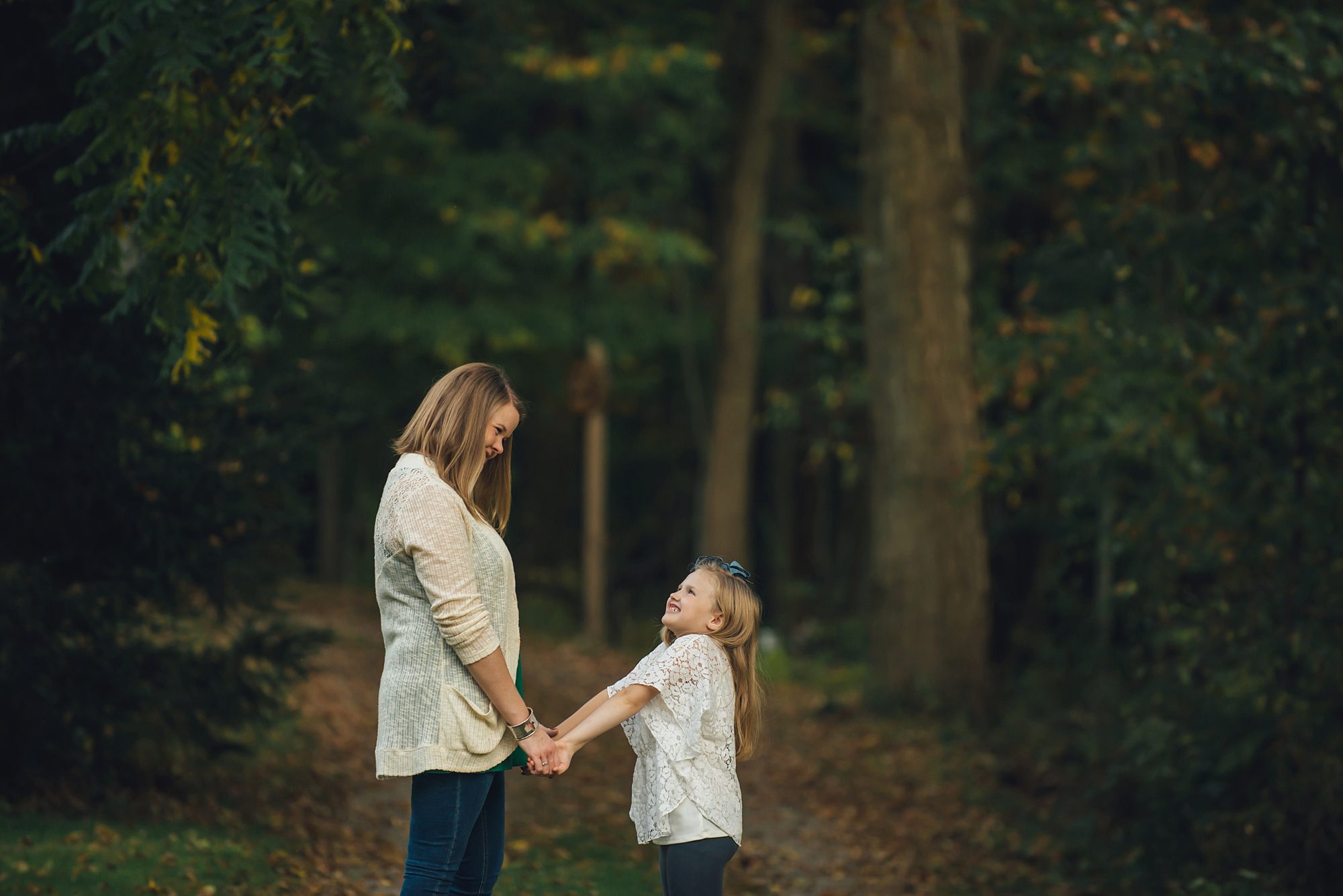 Mom and daughter holding hands looking at each other at Robin Hill Park near Pittsburgh