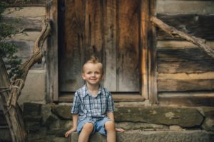 Boy sitting on steps in front of cabin at Robin Hill Park near Pittsburgh