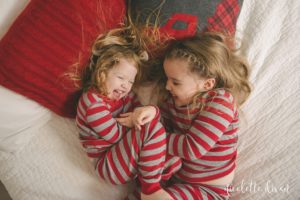 Girls tickling each other on bed wearing matching Christmas pajamas in home in Moon Township near Pittsburgh