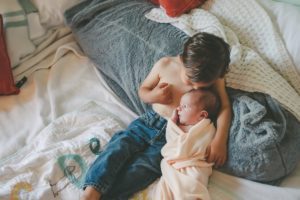 Big brother kissing newborn baby sister on the head in home in Robinson Township in Pittsburgh