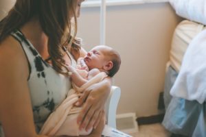 Mom holding newborn baby girl in rocking chair in home in Robinson Township near Pittsburgh