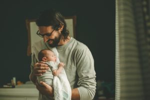 Dad holding newborn baby boy by window in home in Coraopolis near Pittsburgh
