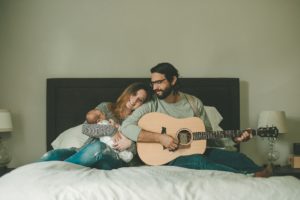 Dad playing guitar while mom is holding newborn baby boy in home in Coraopolis near Pittsburgh