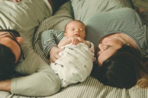 Newborn baby boy laying next to mom on bed in home in Coraopolis near Pittsburgh
