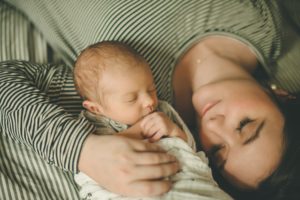 Newborn baby boy laying next to mom on bed in home in Coraopolis near Pittsburgh