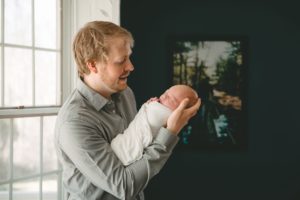 Dad looking at newborn baby girl in home in Sewickley near Pittsburgh