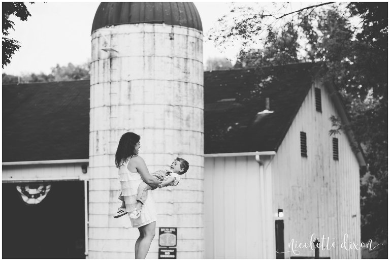 A black and white image of a young boy and his mom playing near a barn and silo at Round Hill Park near Pittsburgh