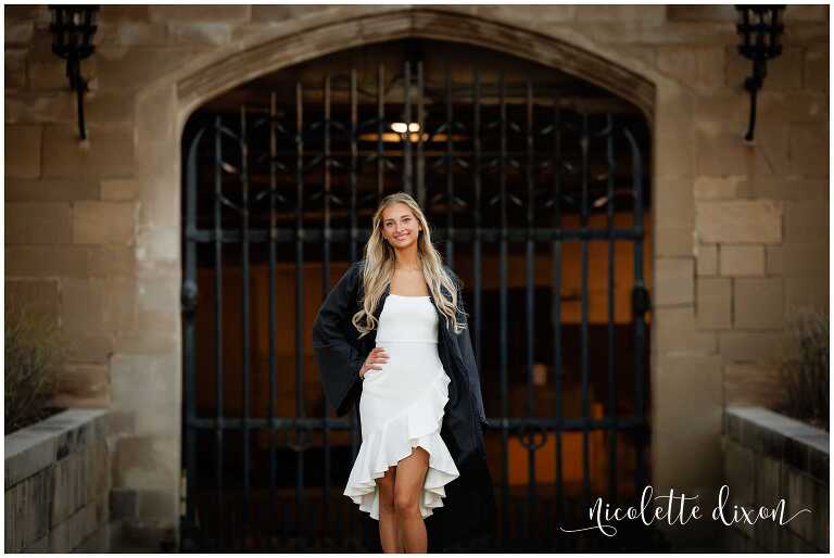 College graduate standng in front of gate at the Cathedral of Learning at the University of Pittsburgh 