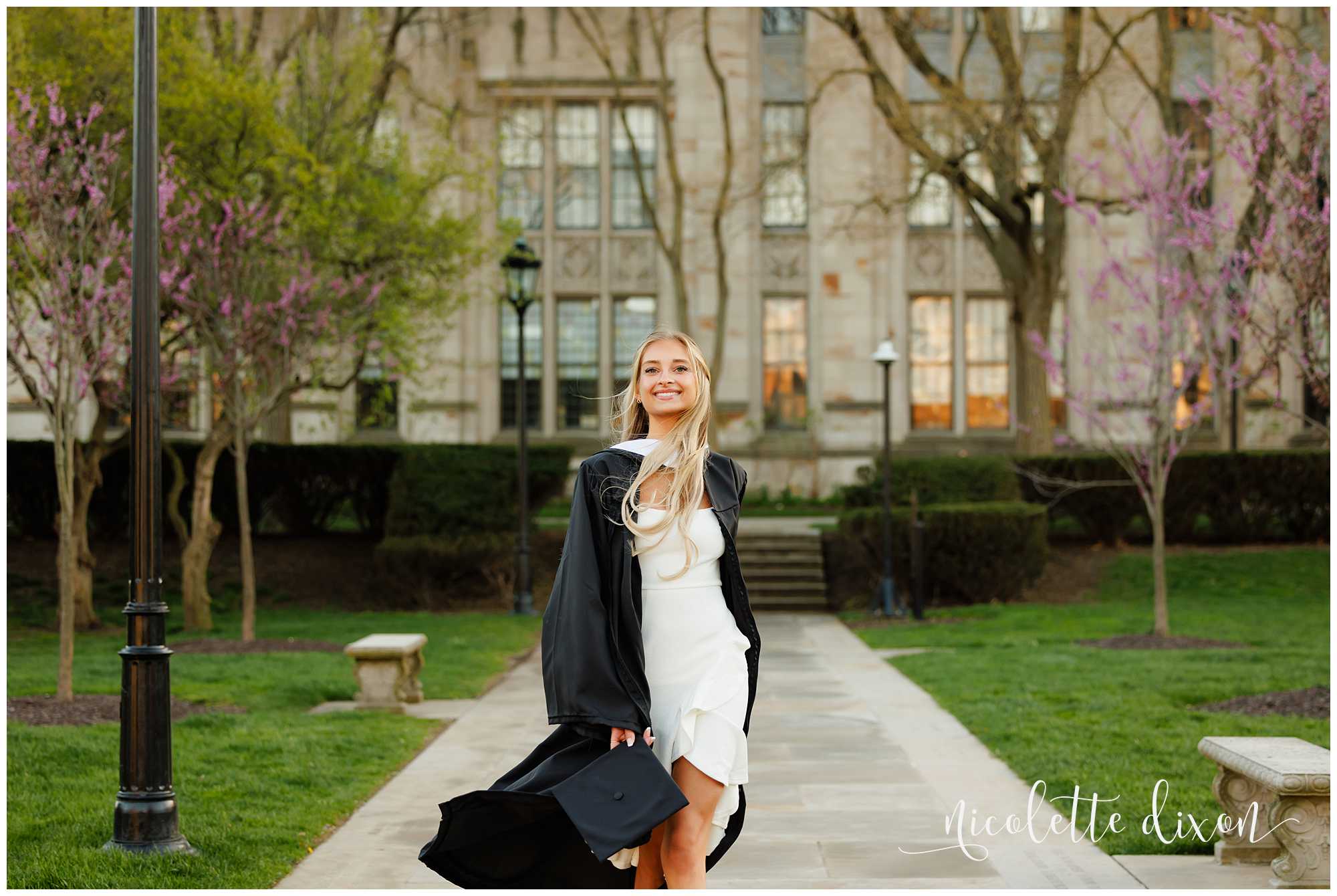 College graduate walking down sidewalk in front of the Cathedral of Learning at the University of Pittsburgh 