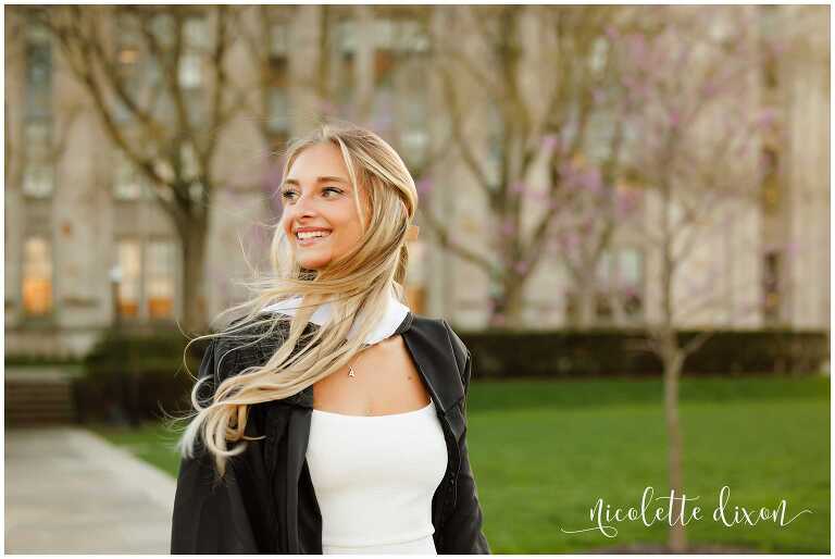 College graduate looking to the side in front of the Cathedral of Learning at the University of Pittsburgh 