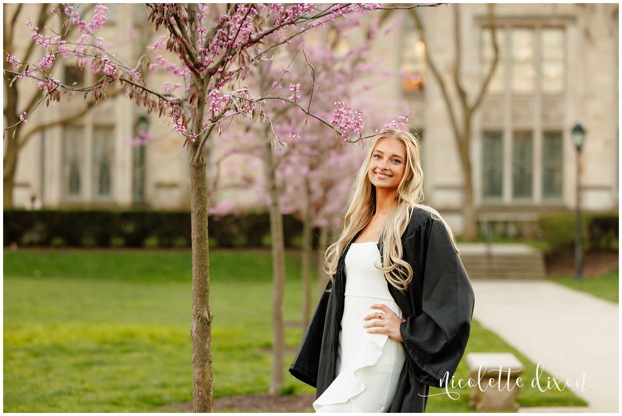 College graduate standing next to tree with purple blossoms in front of the Cathedral of Learning at the University of Pittsburgh 
