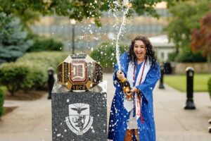 College graduate holding champagne next to ring at Duquesne University in Pittsburgh