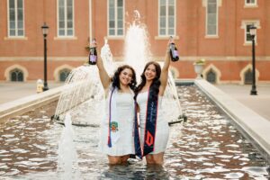 College graduate holding champagne in fountain at Duquesne University in Pittsburgh