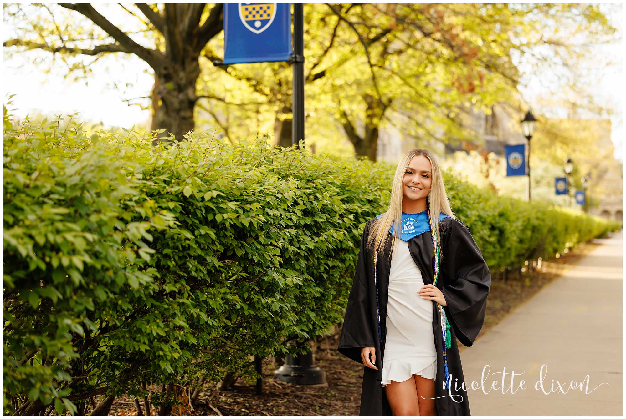 College grad standing in front of the University of Pittsburgh banners