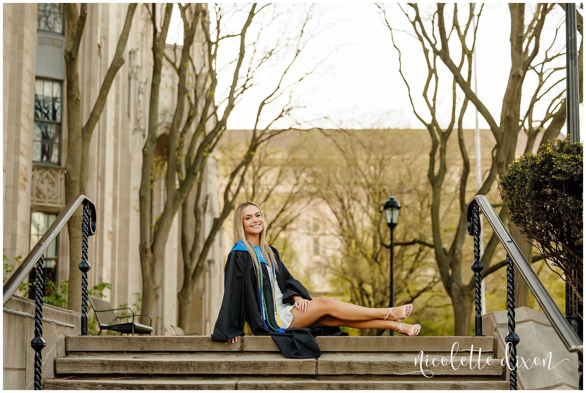 College grad sitting on the stairs in front of the Cathedral of Learning at the University of Pittsburgh