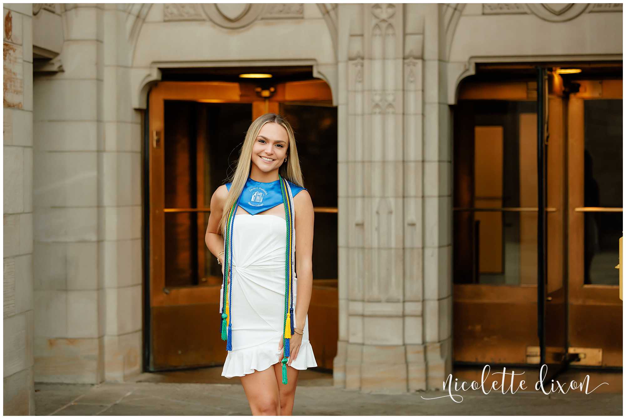 College grad standing in front of the doors at the Cathedral of Learning at the University of Pittsburgh