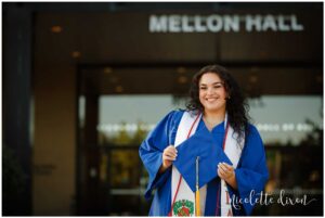 College Graduate Holding Hat in front of Mellon Hall on Duquesne University Campus in Pittsburgh