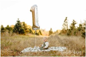 One year old boy sitting next to silver 1 balloon at Aliison's Christmas Tree Farm near Pittsburgh PA