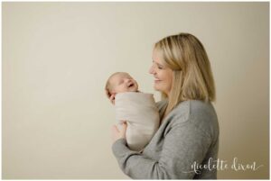 Mom looking at newborn baby smiling in studio in North Fayette Township near Pittsburgh.
