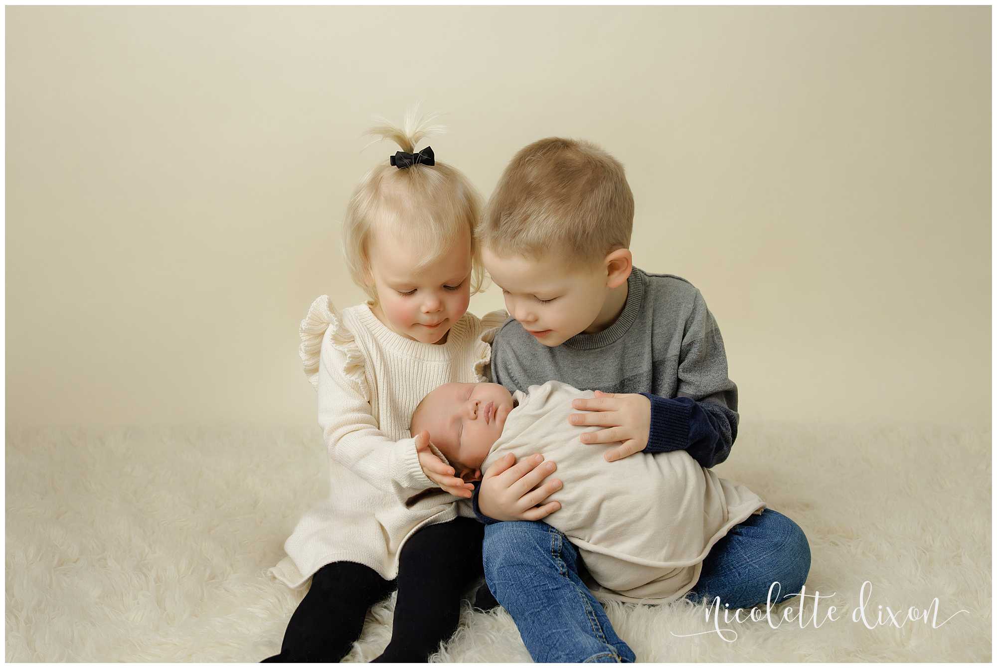 Brother and sister looking at newborn brother in studio in North Fayette Township near Pittsburgh.