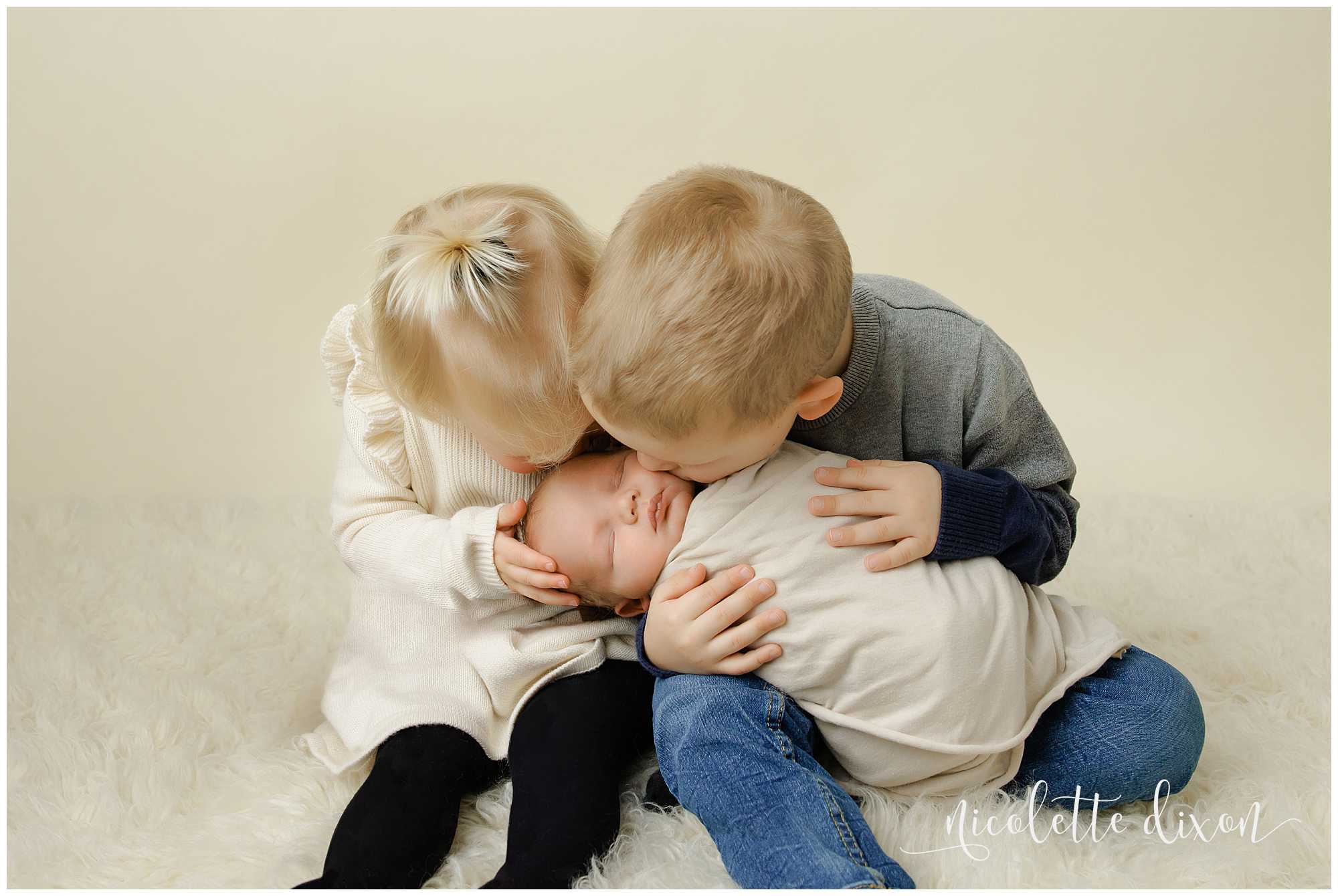 Brother and sister kissing newborn brother in studio in North Fayette Township near Pittsburgh.