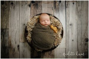 Newborn baby boy laying wrapped in blanket in bowl in studio in North Fayette Township near Pittsburgh.