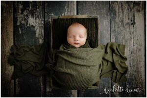 Newborn baby boy covered with green blanket in studio in North Fayette Township near Pittsburgh.
