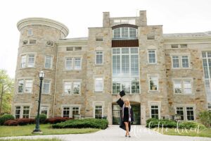 College grad holding hat up in front of Burnett Center at Washington and Jefferson College near Pittsburgh