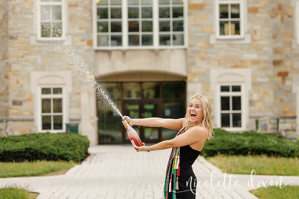 College grad holding champagne in front of Burnett Center at Washington and Jefferson College near Pittsburgh